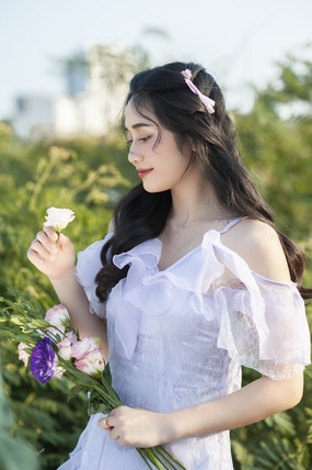 手持鲜花欣赏的亚洲美女摄影图片